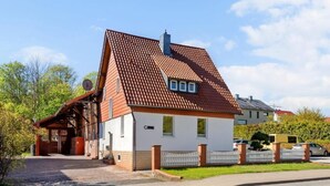 A two-story house with a red-tiled roof, a brick chimney, and a small attached garage. - Harzträume Apartments Wernigerode (Wernigerode)