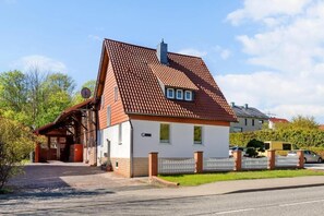 Ein zweigeschossiges Haus mit einem roten Ziegeldach, einem Backsteinsschornstein und einer kleinen angebauten Garage.