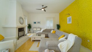 Ein Wohnzimmer mit Sofa, Kamin, Deckenventilator und gelber Wand.