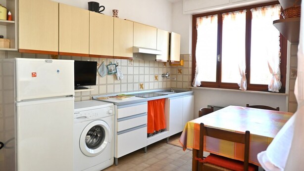 Una cucina compatta con lavatrice, lavello e zona pranzo con tavolo e sedie.