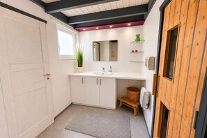 A modern bathroom with a large mirror, white cabinets, and a wooden door. - Wildgans 29 - Classic Scandinavian vacation home for up to 6 people (Mirow)