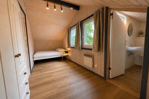 A bedroom with a bed, bedside table, lamp, window, and a view of the outdoors. - Wildgans 29 - Classic Scandinavian vacation home for up to 6 people (Mirow)