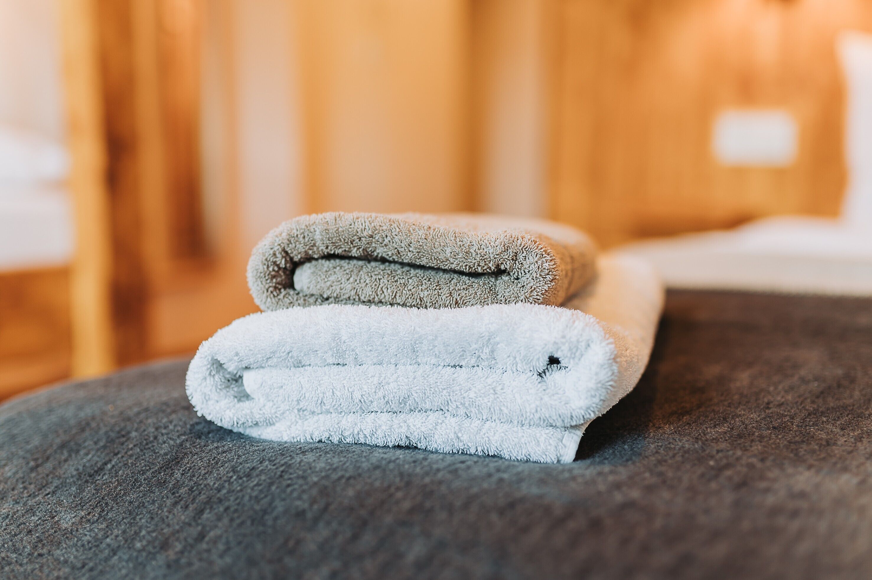 A stack of folded towels on a textured surface, likely in a hotel room.