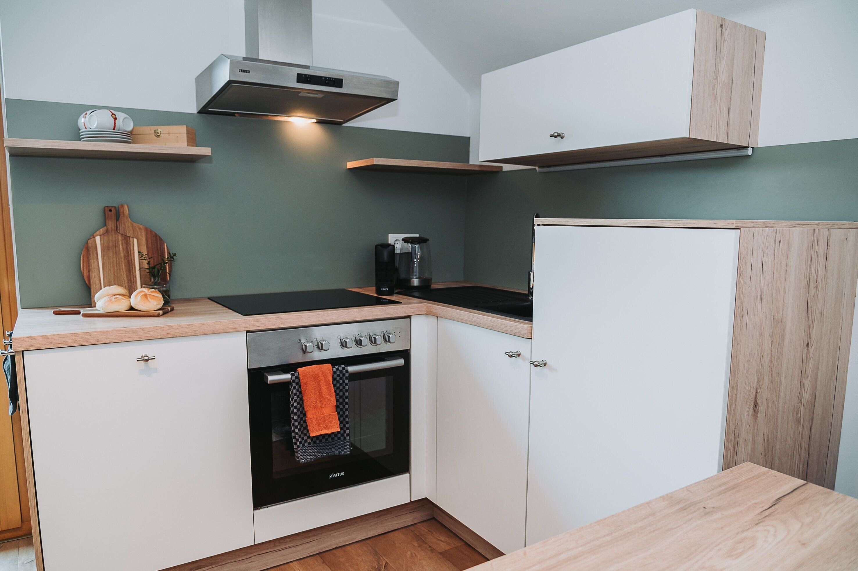 Una cocina compacta con horno empotrado, cafetera y encimeras de madera.