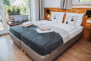Ein modernes Hotelzimmer mit einem großen Bett, einem hölzernen Kopfteil und Blick auf Grün.