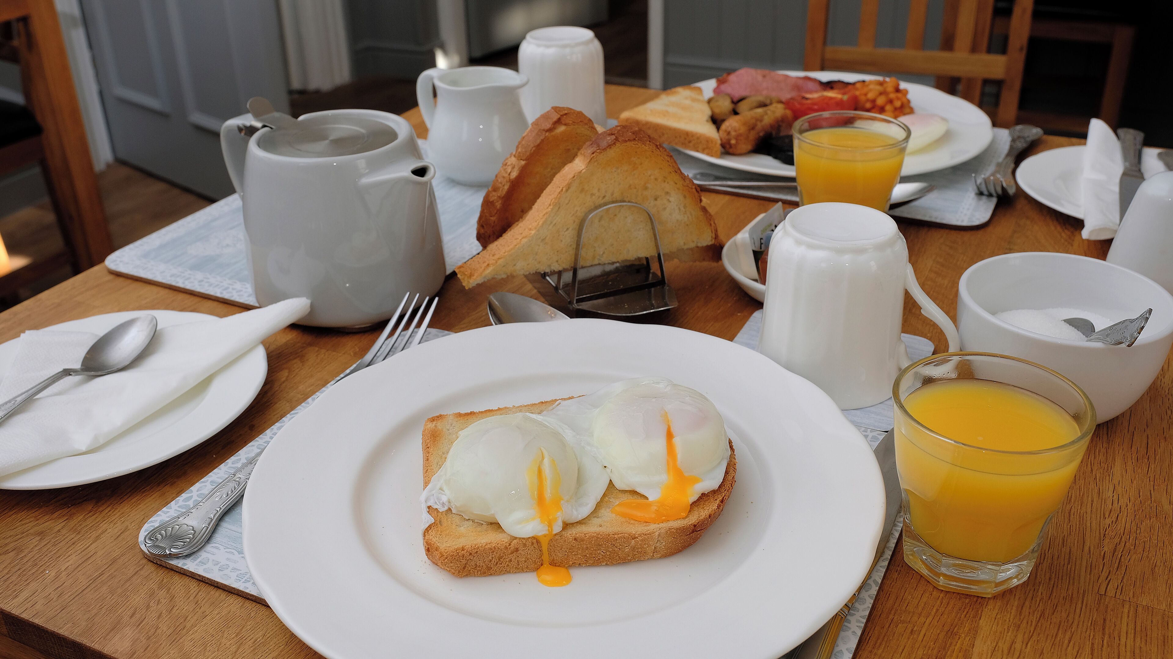 A breakfast setting with toast, eggs, and orange juice on a wooden table.