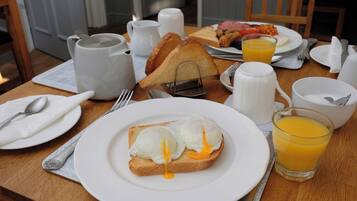 A breakfast setting with toast, eggs, and orange juice on a wooden table.