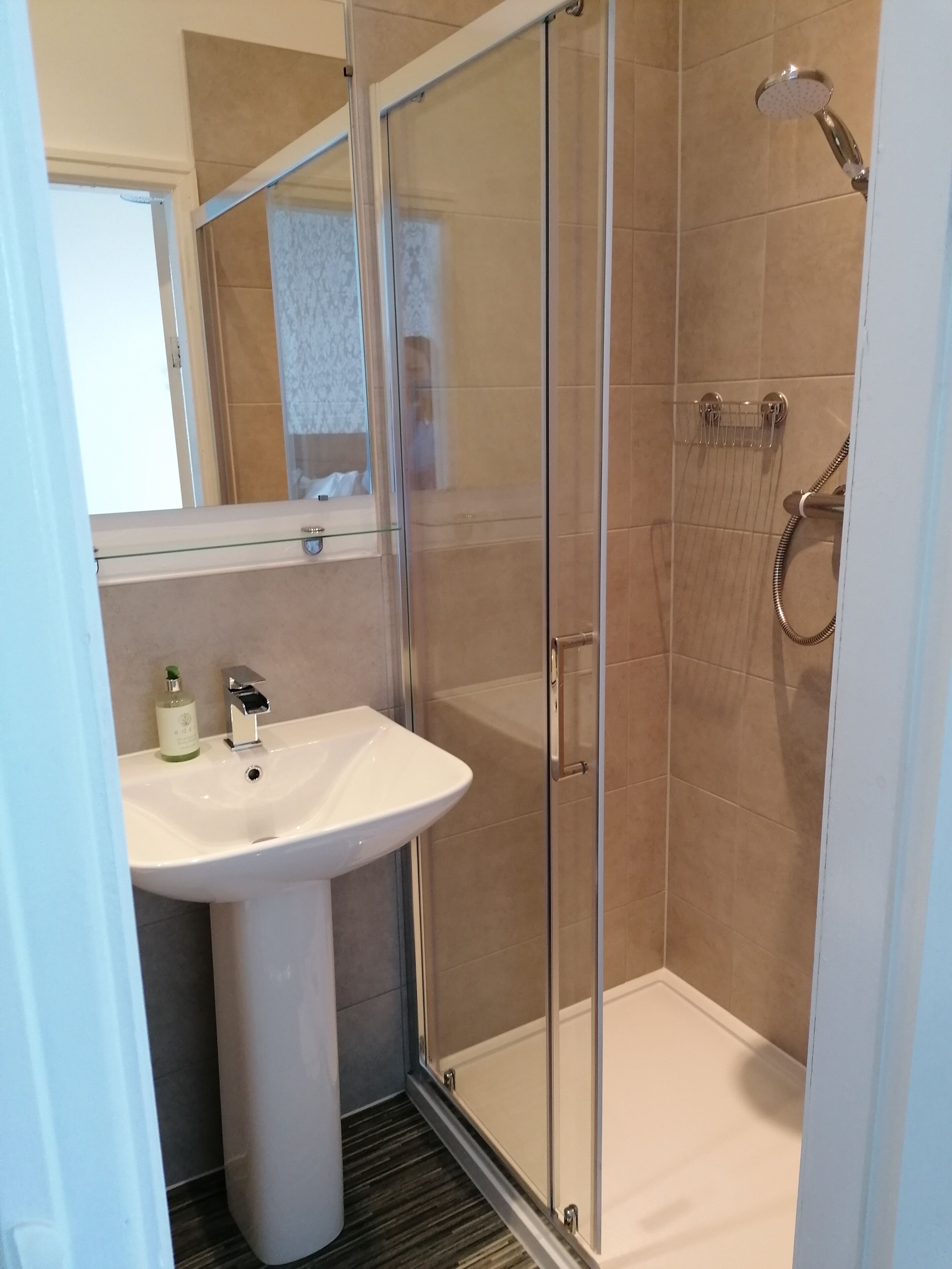 A bathroom with a glass-enclosed shower, a white sink, and a mirror above the sink.