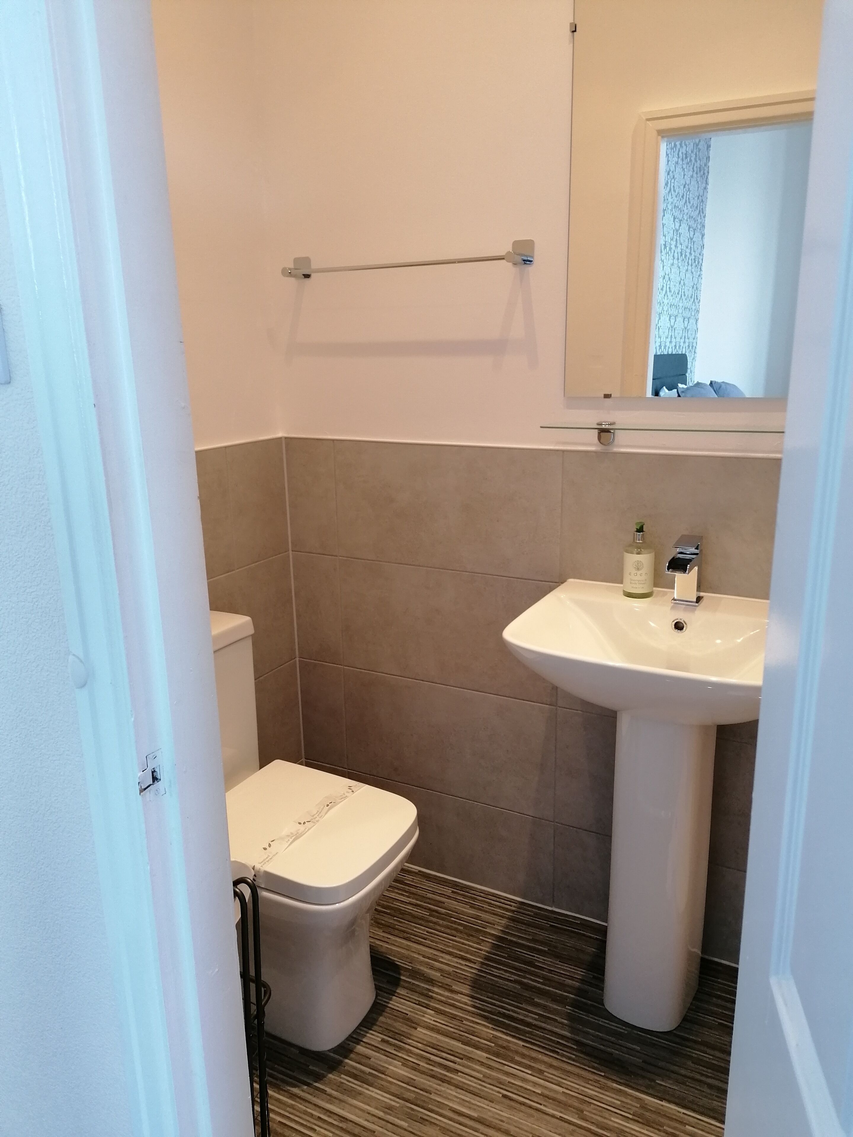 A small bathroom with a toilet, a sink, and a mirror.