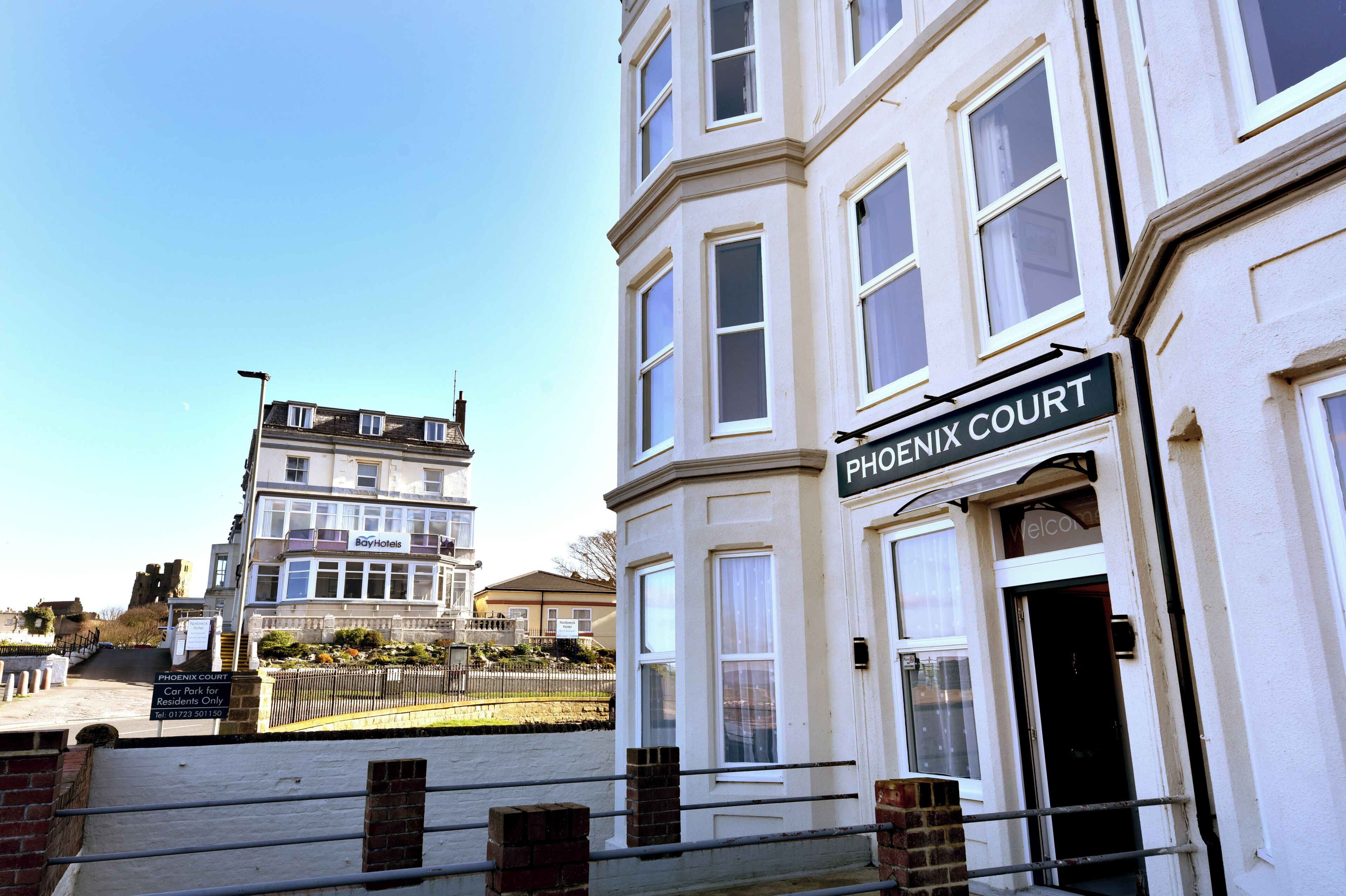 A building with a sign reading 'Phoenix Court' and a 'BoyHotels' sign above the entrance.