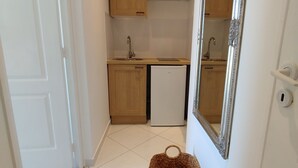 A compact kitchen with wooden cabinets, a white refrigerator, and a large mirror.