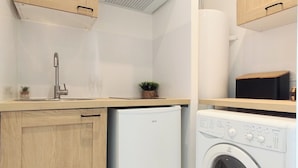 A compact kitchen with wooden cabinets, a built-in dishwasher, and a front-loading washing machine.