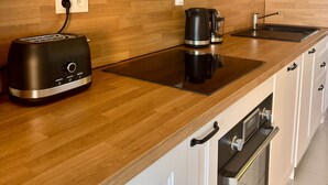Una cuina moderna amb taulells de fusta, forn integrat, cafetera i torradora.