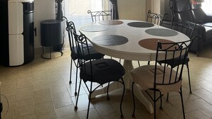 A dining area with a round table, chairs, a ceiling fan, and artwork on the walls. - Parenthese à Montady - 6personnes - PMR - Terrasses (Montady)