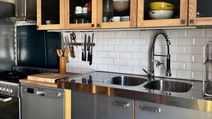 A modern kitchen with stainless steel appliances, wooden cabinets, and a white tiled backsplash. - Parenthese à Montady - 6personnes - PMR - Terrasses (Montady)