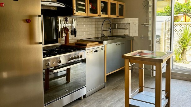 A modern kitchen with stainless steel appliances, wooden cabinets, and a ceiling fan. - Parenthese à Montady - 6personnes - PMR - Terrasses (Montady)