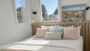 A bedroom with a bed, two windows, a painting, and a lamp. - IN THE SHADE OF THE OLIVE TREE IN GRAU D'AGDE (Agde)