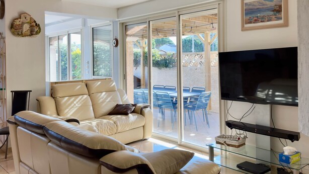A spacious living area with a large sofa, a flat-screen TV, and a glass coffee table. - IN THE SHADE OF THE OLIVE TREE IN GRAU D'AGDE (Agde)