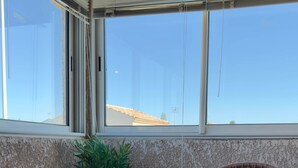 A balcony with a wicker chair, a glass table, and a potted plant. - IN THE SHADE OF THE OLIVE TREE IN GRAU D'AGDE (Agde)