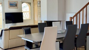 A modern living room with a dining area, a sofa, a flat-screen TV, and a staircase. - IN THE SHADE OF THE OLIVE TREE IN GRAU D'AGDE (Agde)