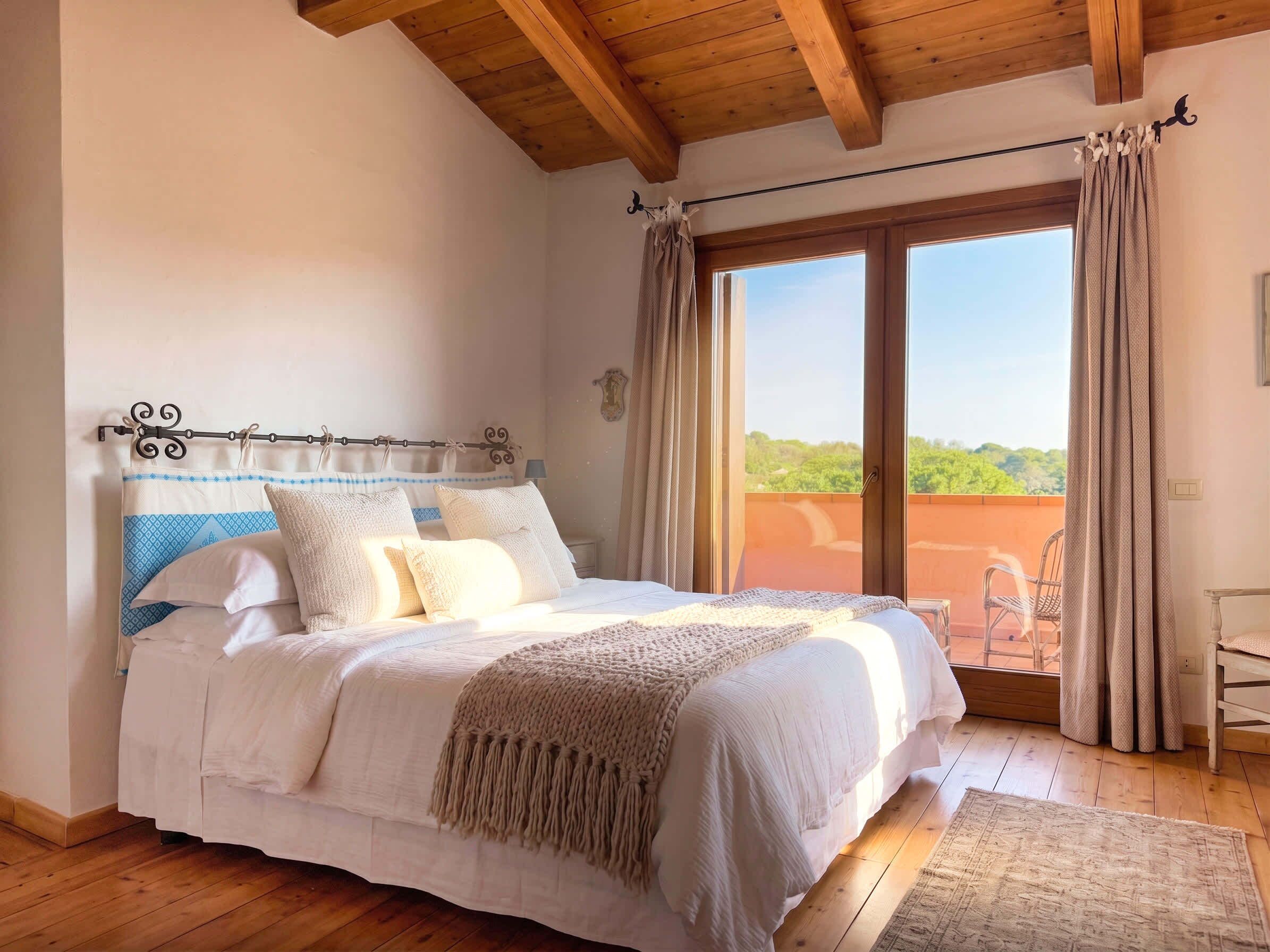 Une chambre avec un plafond en bois, un lit recouvert de linge de lit blanc, une vue à travers une porte coulissante et une petite table près de la porte.