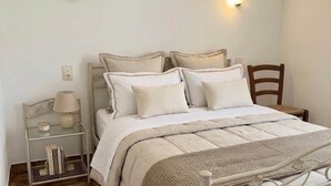 A bedroom with a bed, bedside table, lamp, and wall-mounted light fixture. - THE TAMARISSIERE RETREAT (Agde)