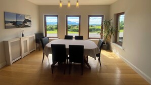 Zona pranzo con tavolo e sedie, ampie finestre con vista e lampadario.