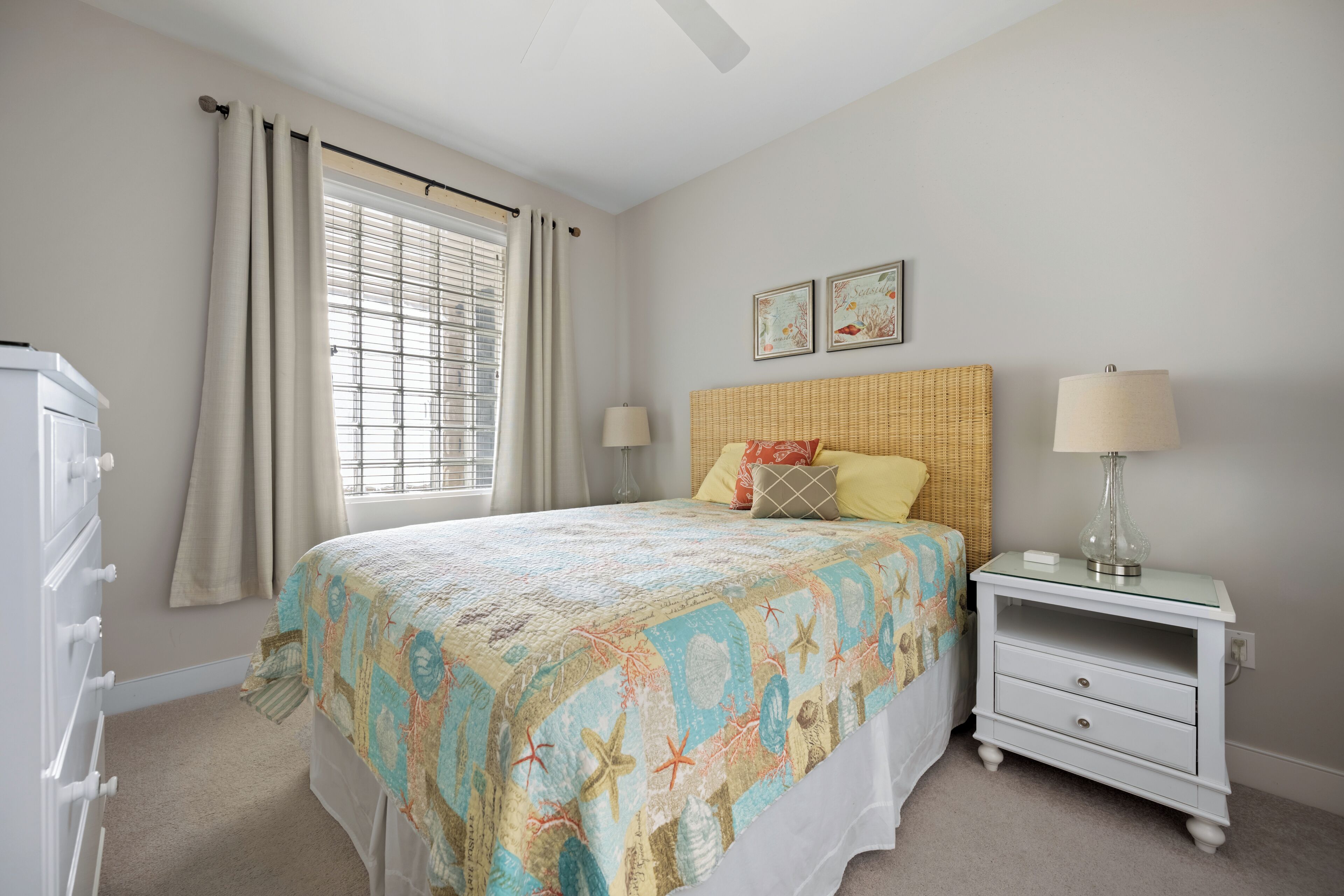 A bedroom with a bed, a nightstand, a dresser, and a window with curtains.