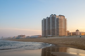 Ein Hochhotel mit mehreren Balkonen, direkt neben einem Strand gelegen.