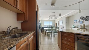 A kitchen with granite countertops, wooden cabinets, stainless steel appliances, and a dining area with chairs and a table. - Three bedroom oceanfront condo in the luxurious Gateway Grand! (Ocean City)