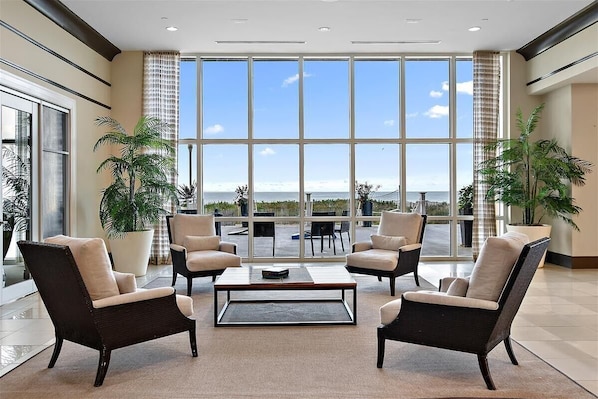 Eine geräumige Lobby mit großen Fenstern und Meerblick, bequemen Sitzgelegenheiten und Topfpflanzen.