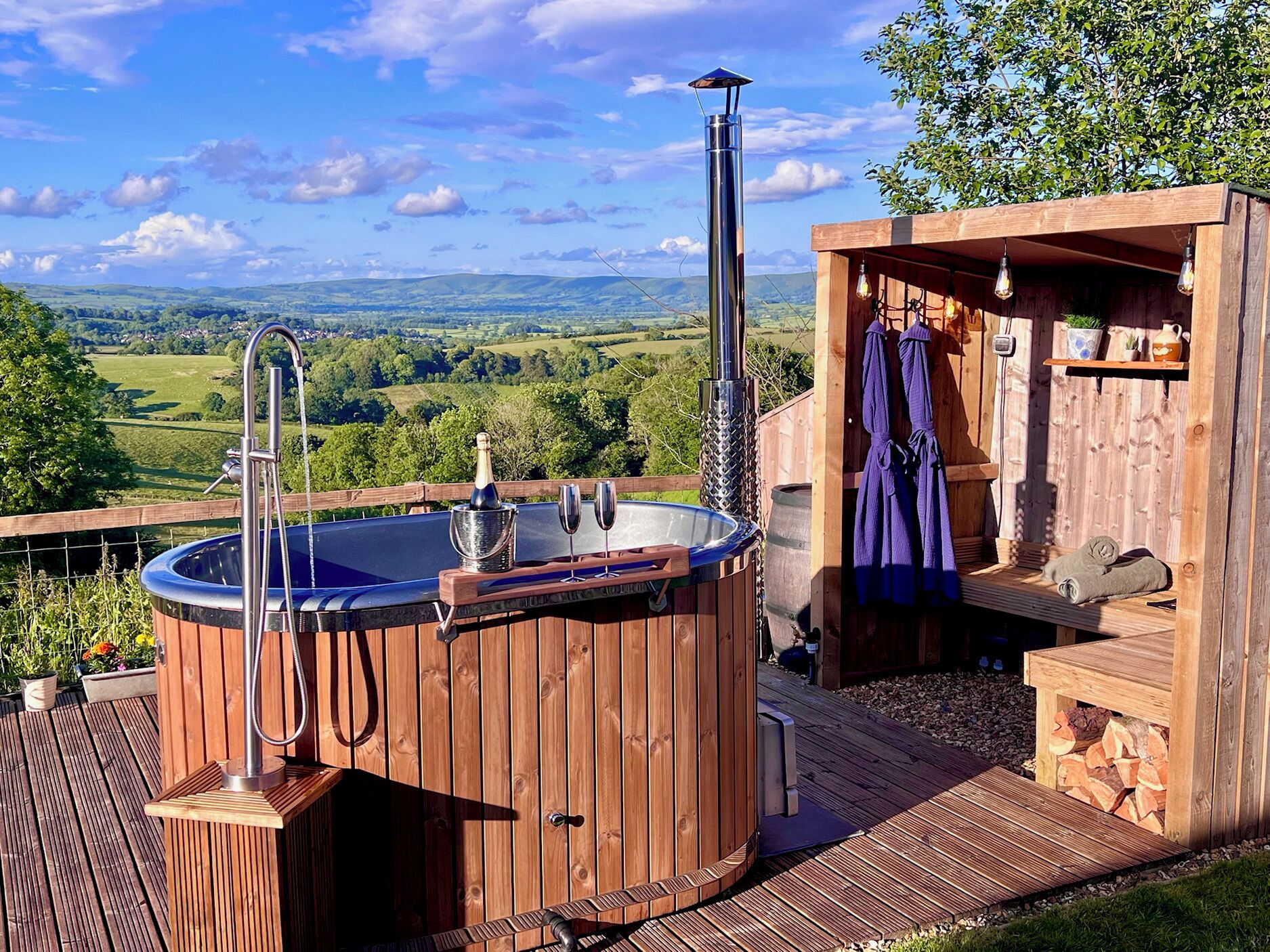 Un jacuzzi de madera con vistas al campo, una terraza de madera y una zona de sauna.