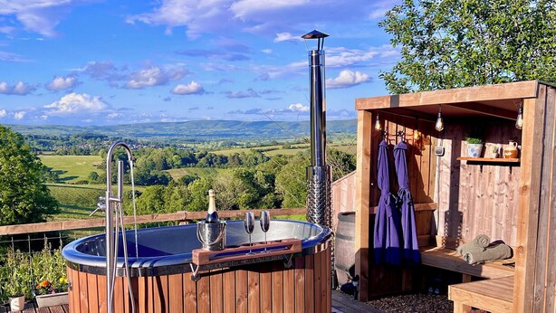 Un jacuzzi de madera con vistas al campo, una terraza de madera y una zona de sauna.