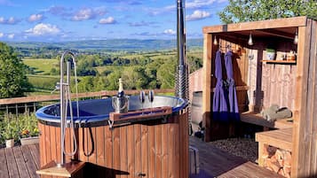 Un jacuzzi de madera con vistas al campo, una terraza de madera y una zona de sauna.