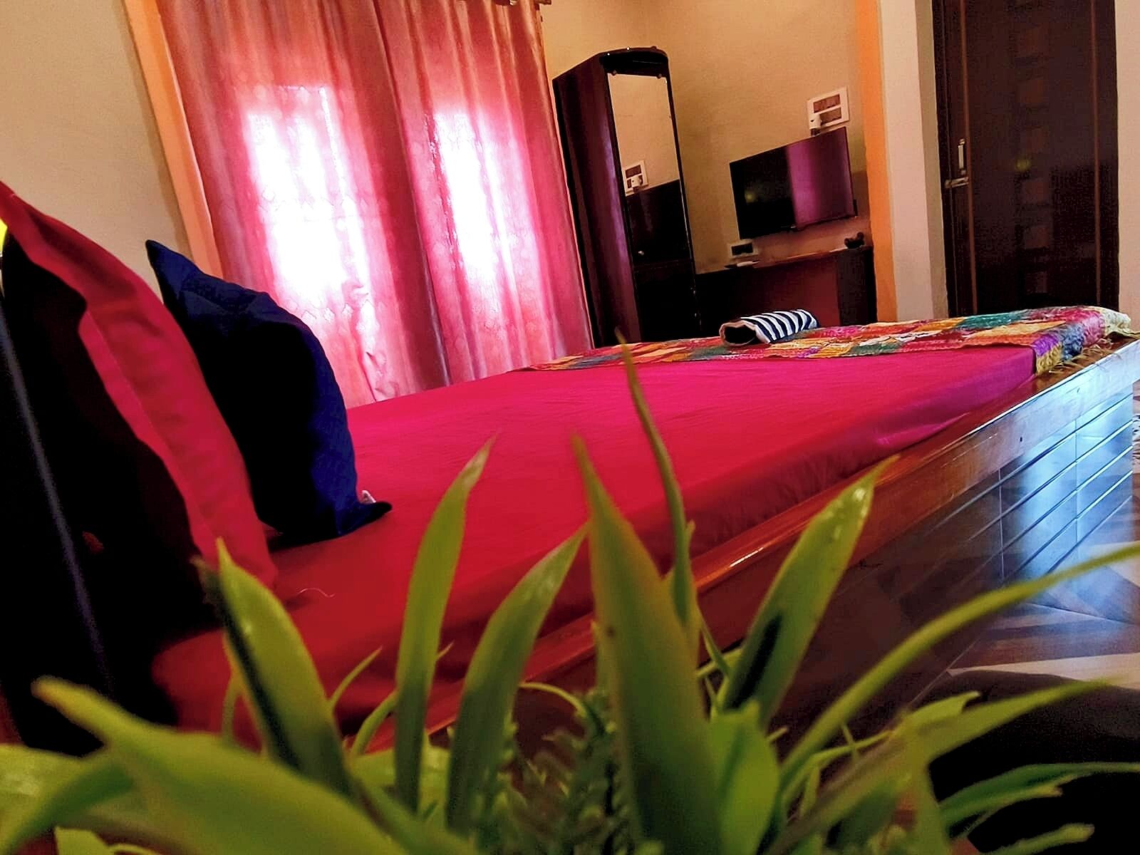 Hotellihuone, jossa on sänky, peili, televisio ja ovi.