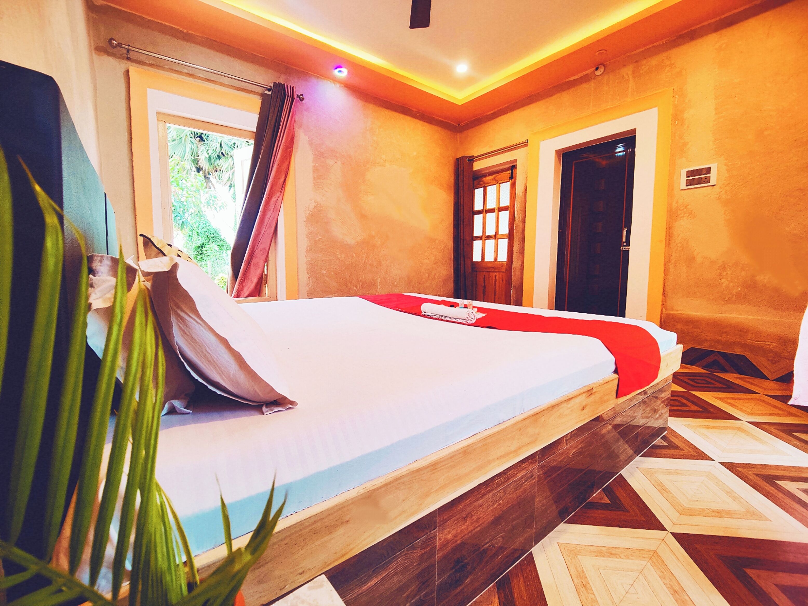 A room with a bed, a window with curtains, a door, and a patterned floor.