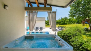 A hot tub with a view of a pool and outdoor seating area. - Villa Bateli by Villas Guide (Barban)