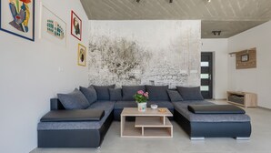 A modern living room with a sectional sofa, a coffee table, and a textured wall. - Villa Bateli by Villas Guide (Barban)