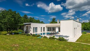 A modern house with a swimming pool, a covered outdoor seating area, and a well-maintained lawn. - Villa Bateli by Villas Guide (Barban)