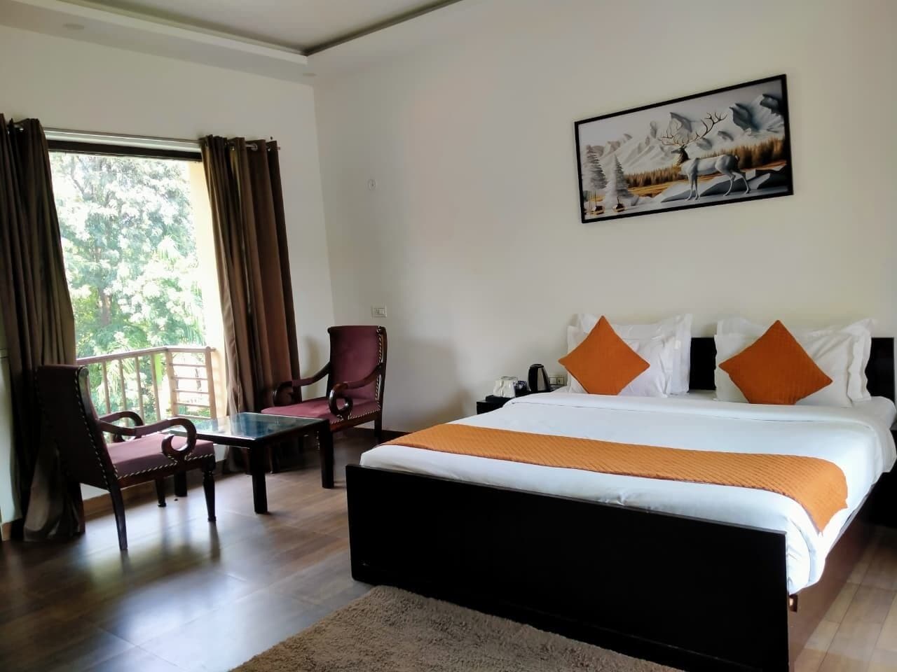 Habitación de hotel con una cama grande, un escritorio, una silla y un ventanal con cortinas.