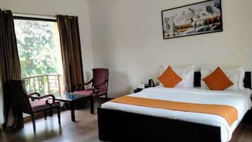 Habitación de hotel con una cama grande, un escritorio, una silla y un ventanal con cortinas.