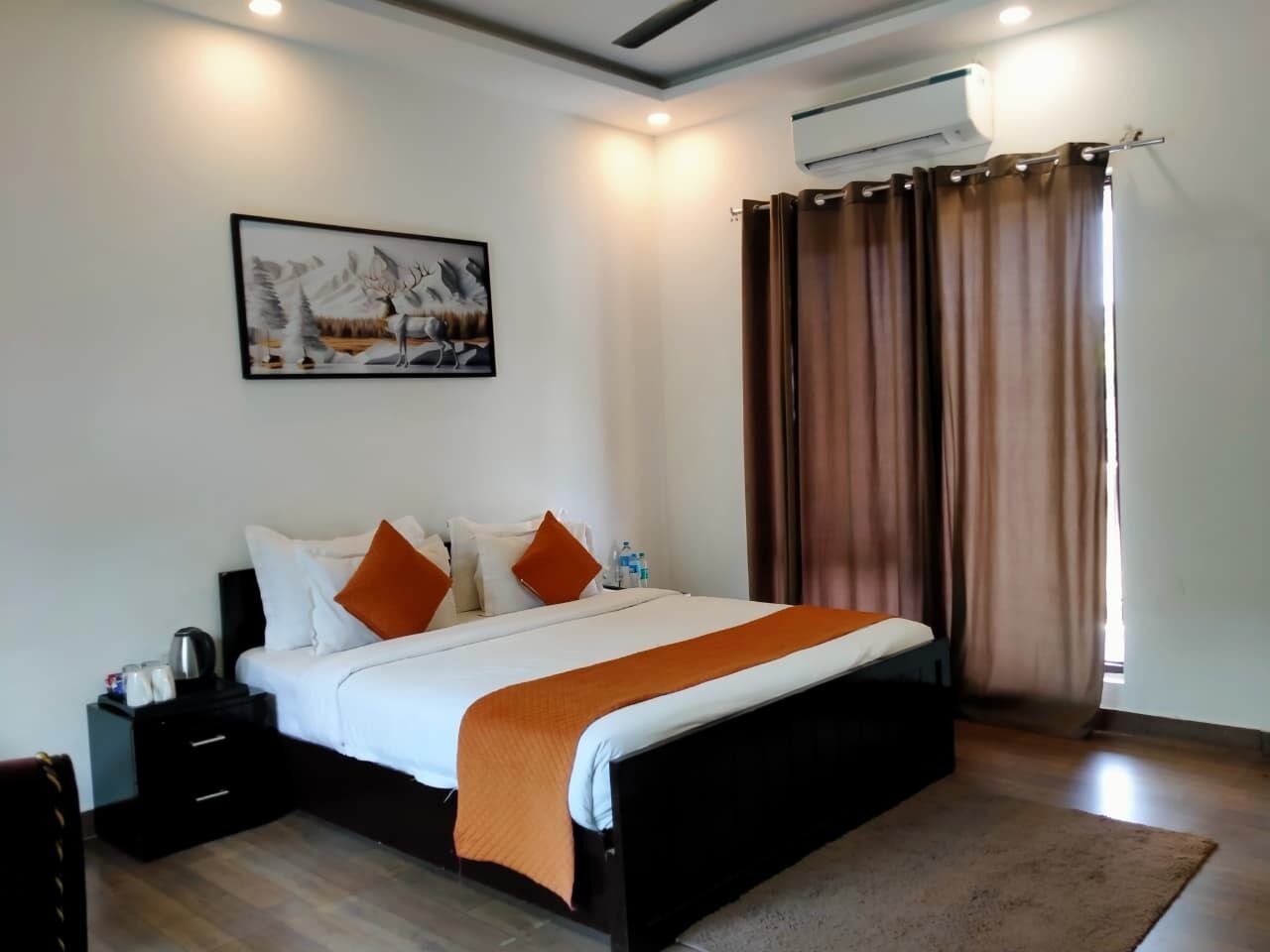 A bedroom with a bed, a nightstand, a wall-mounted air conditioner, and a window with curtains.