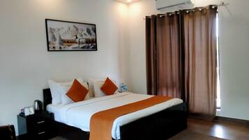 A bedroom with a bed, a nightstand, a wall-mounted air conditioner, and a window with curtains.