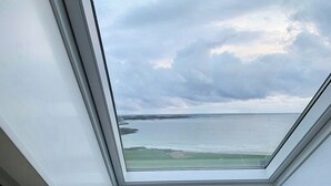 Um claraboia com vista para um céu nublado e um corpo d'água.