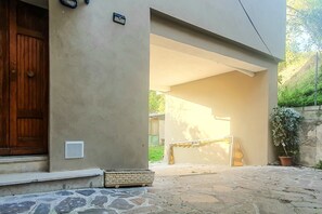 A building entrance with a wooden door, a small outdoor seating area, and a stone-paved path leading to a covered patio. - Casa Chiara - In the Heart of Authentic Abruzzo (San Martino)