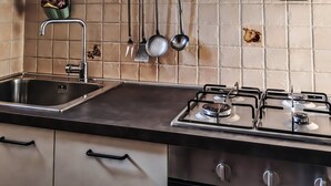 A kitchen with a stainless steel sink, a gas stove, and hanging kitchen utensils. - Casa Chiara - In the Heart of Authentic Abruzzo (San Martino)