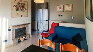 A living room with a fireplace, a blue sofa, red chairs, and artwork on the walls. - Casa Chiara - In the Heart of Authentic Abruzzo (San Martino)