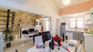 Un soggiorno moderno con zona pranzo, cucina e parete in pietra.