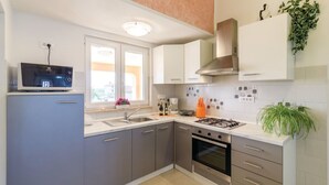 Una cucina moderna con mobili grigi, forno integrato, piano cottura a gas e microonde sul piano di lavoro.