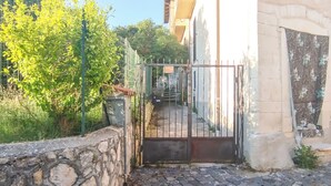 A stone wall, a metal gate, and a paved path leading to a building. - Casa Chiara (Picenze di Barisciano)